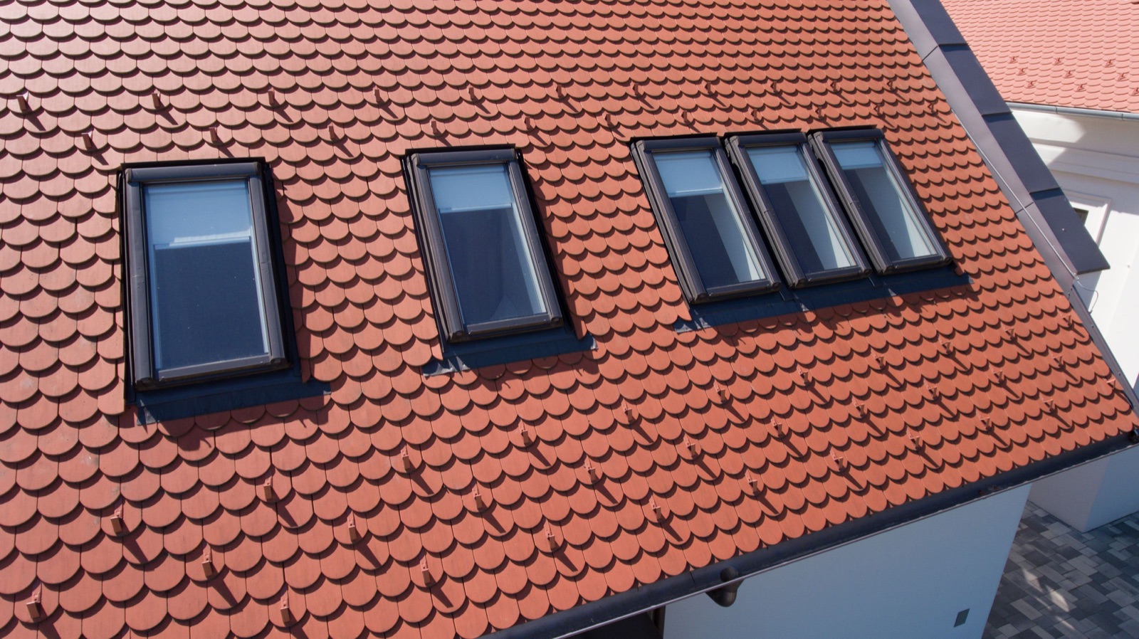 Cinci ferestre de mansardă Roto Designo R4 montate pe un acoperiș din țiglă ceramică roșie